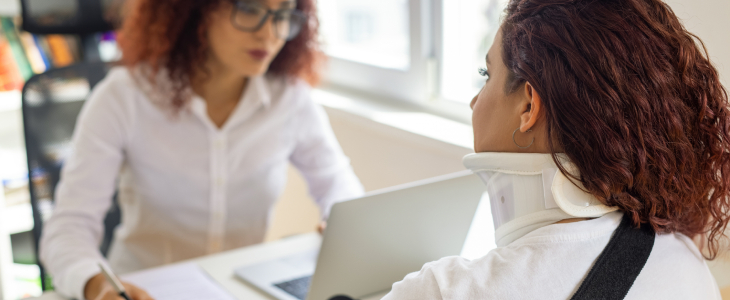 Woman with neck brace speaking with an attorney