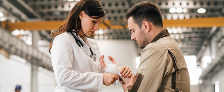 Doctor helping manual worker with an arm injury