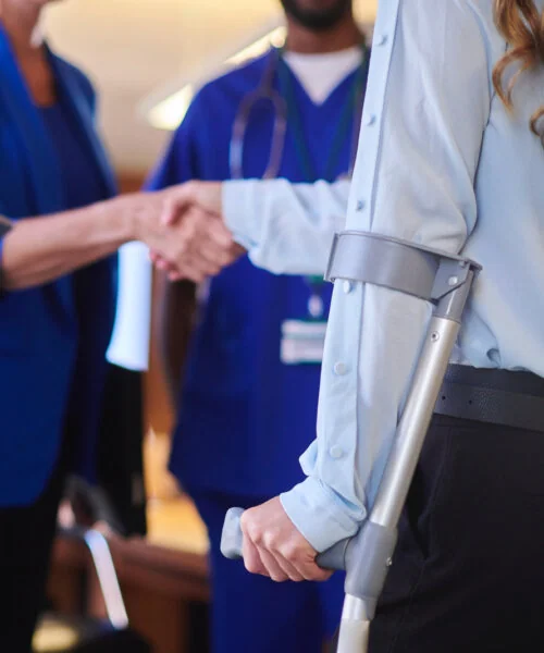 Woman with a crutch shaking hands with doctors